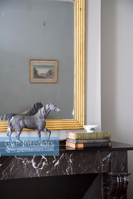 Horse statue and books on marble mantelpiece