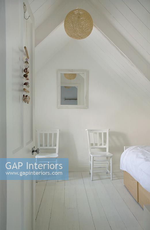 White attic bedroom with two chairs