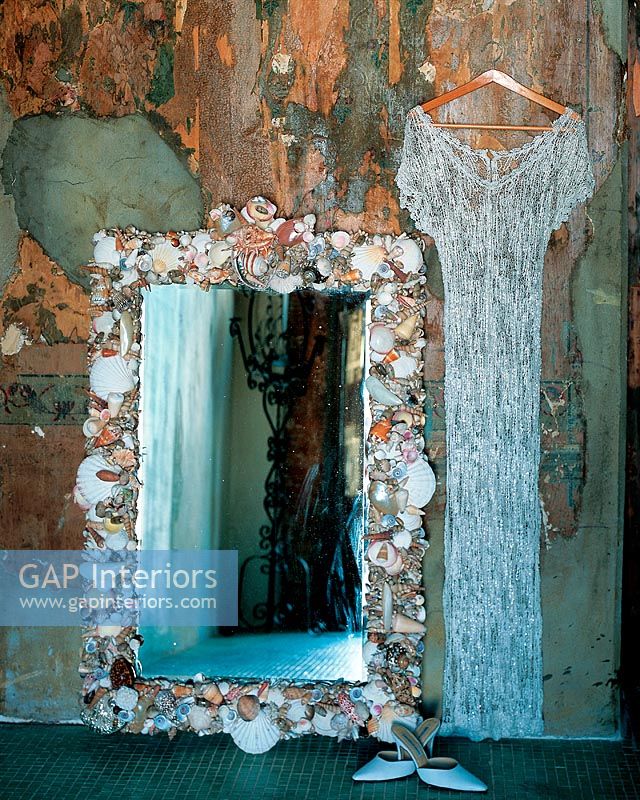 A mirror with a shell frame and a dress