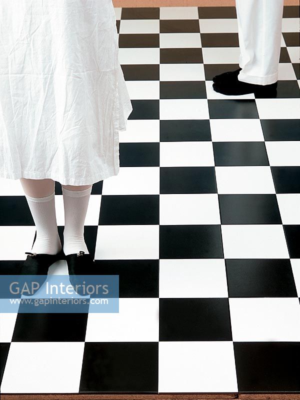 Low section of man and woman standing on checked floor