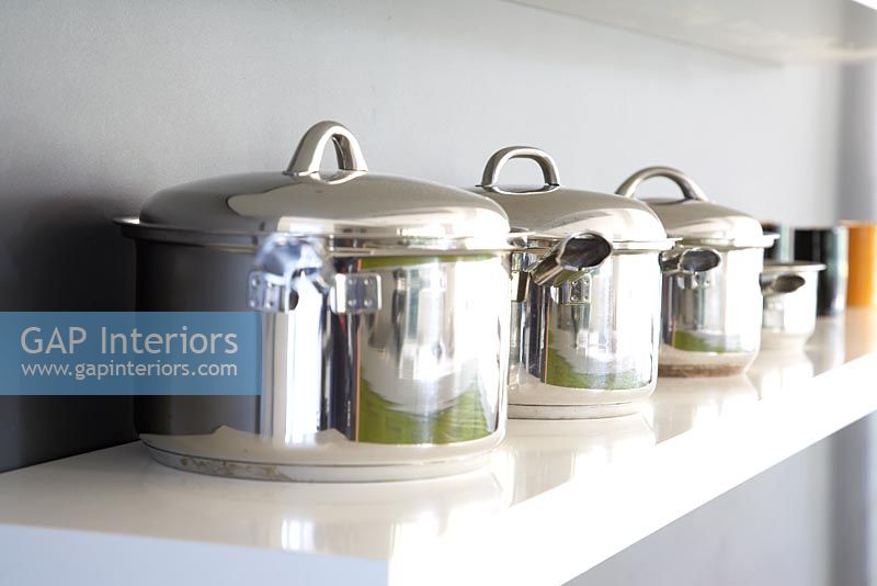 Collection of saucepans on kitchen shelf