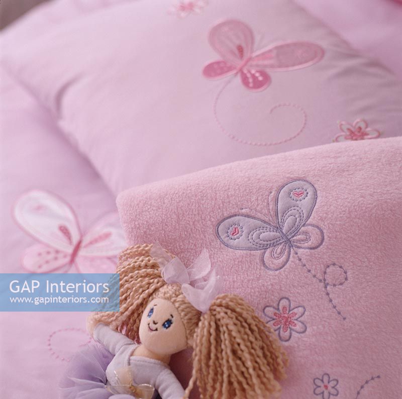 Toy doll on pink pillow, close-up