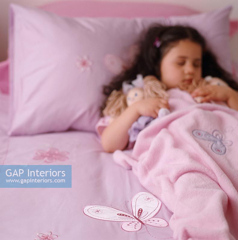 Girl sleeping on bed with doll
