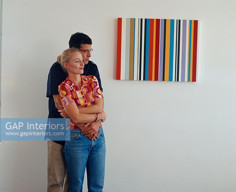 Man holding a woman next to a modern painting