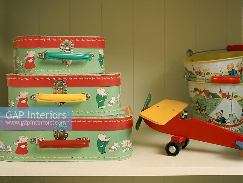 Child's luggage and toy plane on wooden shelf