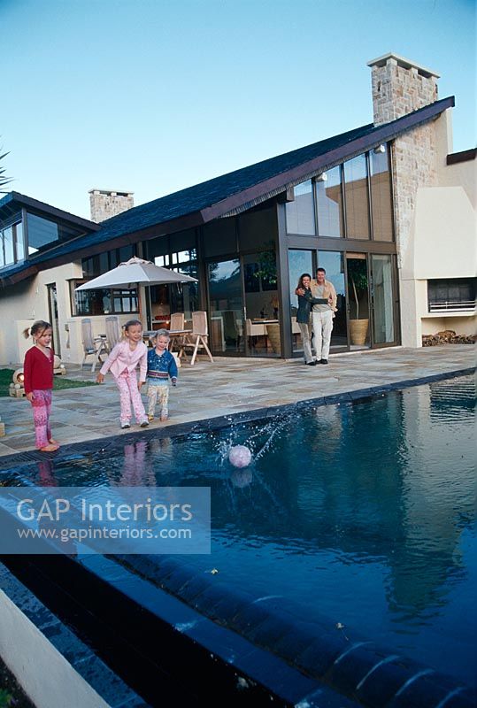Family playing with a ball near a swimming pool