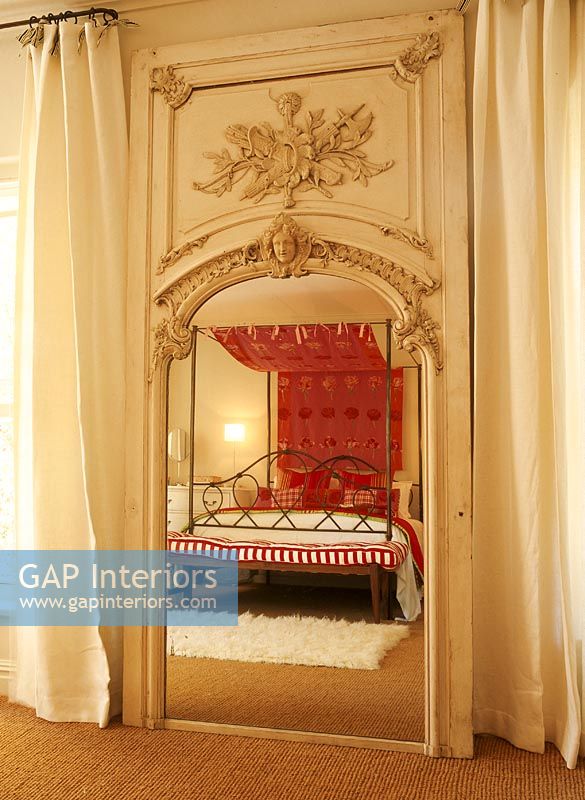 View of a four poster bed reflected in a full length mirror