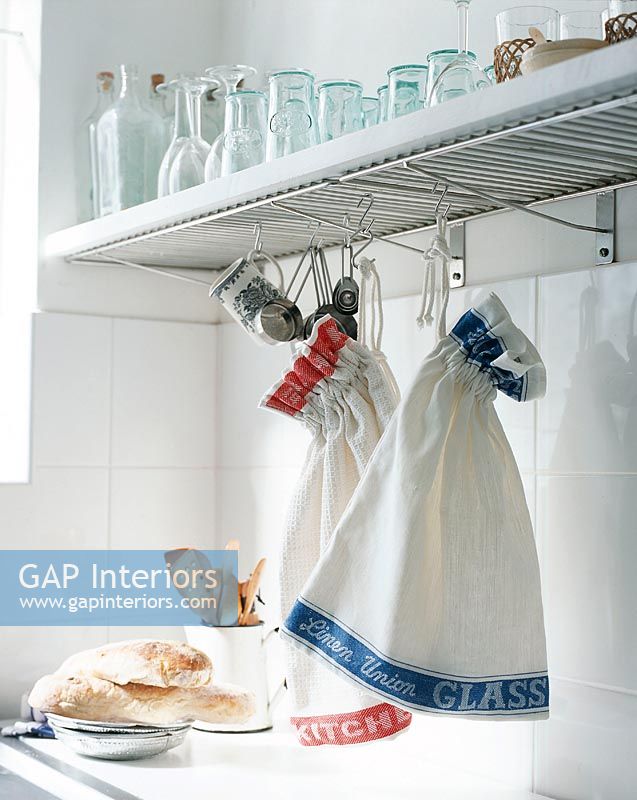 Glasses on shelf with bags made from tea towels hanging on hook