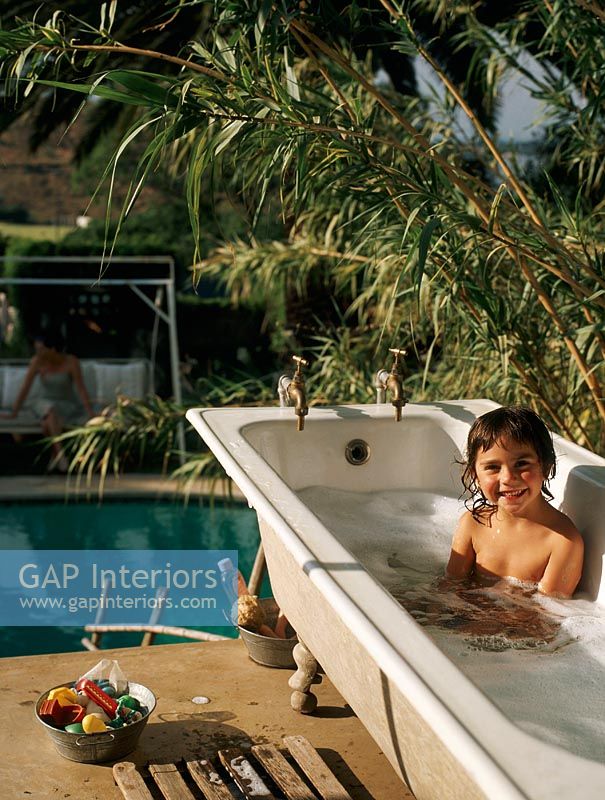 Child bathing in an outdoor bathtub