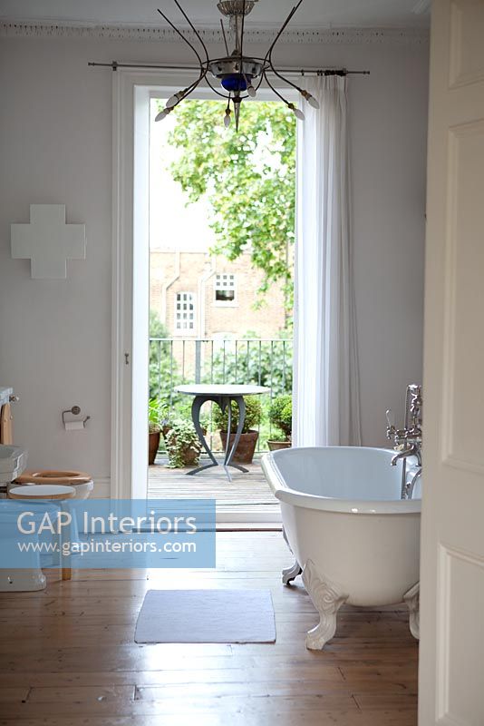 Roll top bath in bathroom with stripped floors