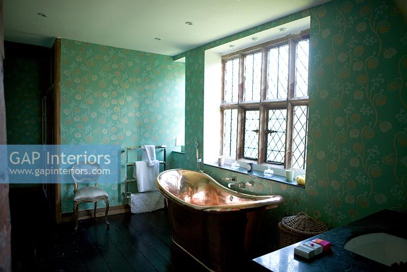 Copper bath under lead paned window in traditional bathroom