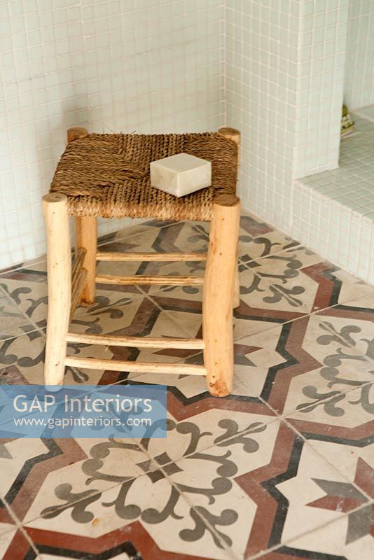 Small wooden stool on patterned tiled floor