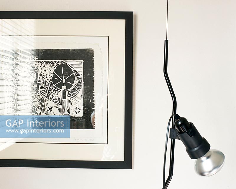 A contemporary white and black drawing on the wall and a lamp