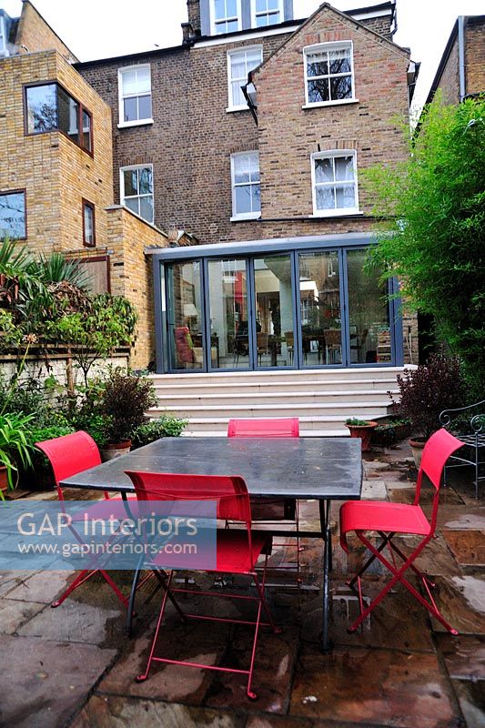 Modern table and chairs in paved garden 