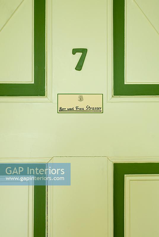Number and name plaque on wooden door, detail