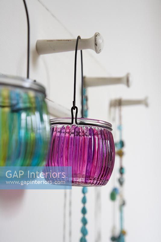 Colourful glass lanterns on coat hooks 