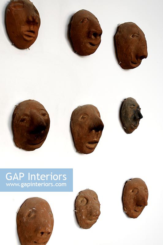 Collection of clay heads on wall, detail