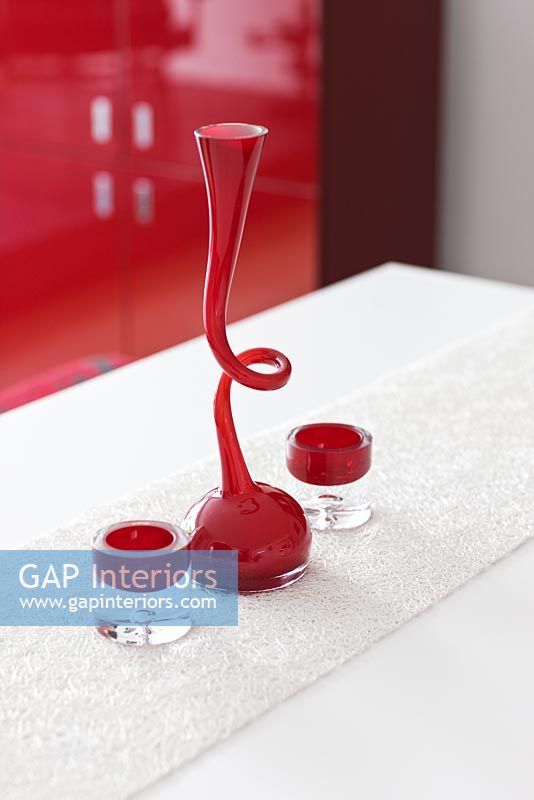 Detail of red curvy candle stick and tea light holders on white table