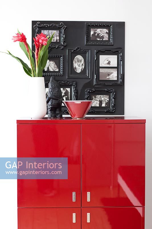 Red glossy cabinet with flower arrangement and photo display
