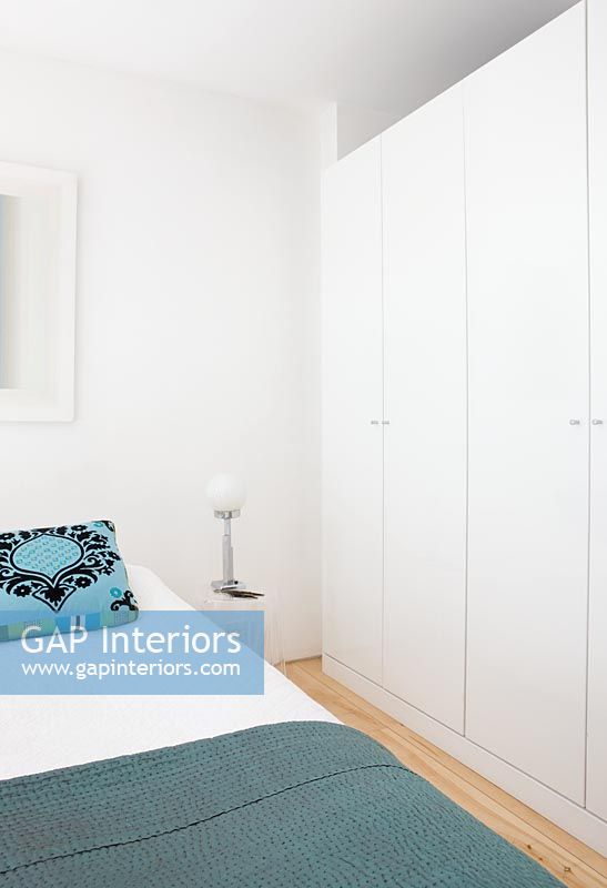 Bedroom with turquoise patterned cushion and white wardrobe