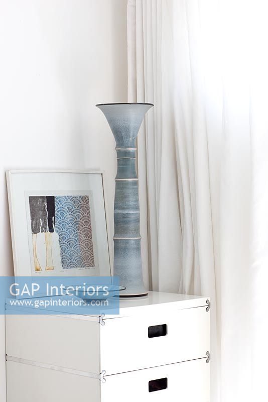 Grey pottery candlestick on white bedside cabinet