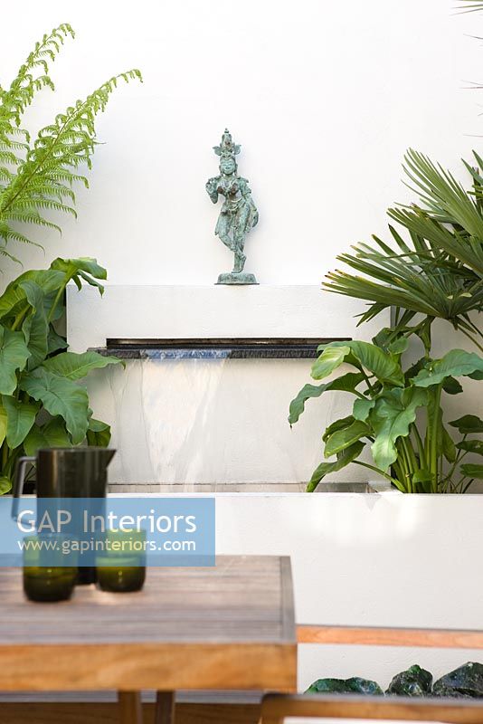 Water feature in urban garden with statue on built in shelf above
