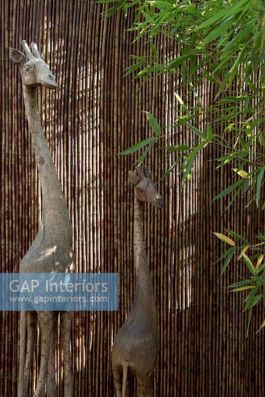 Wooden giraffe sculptures by bamboo fence