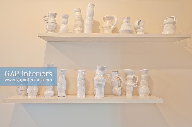 Display of pottery on white shelves
