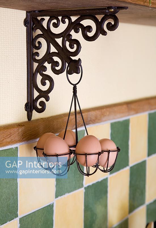 Eggs in wire work basket suspended from wooden shelf
