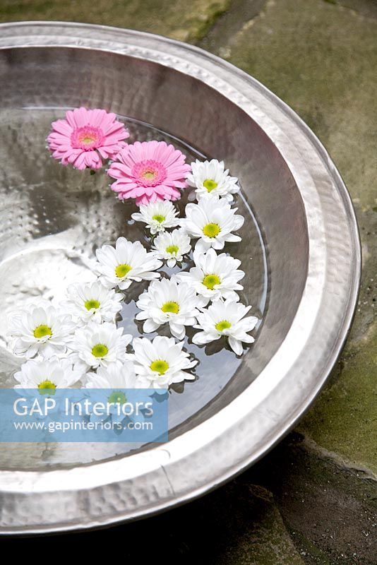 Flowers floating in silver bowl