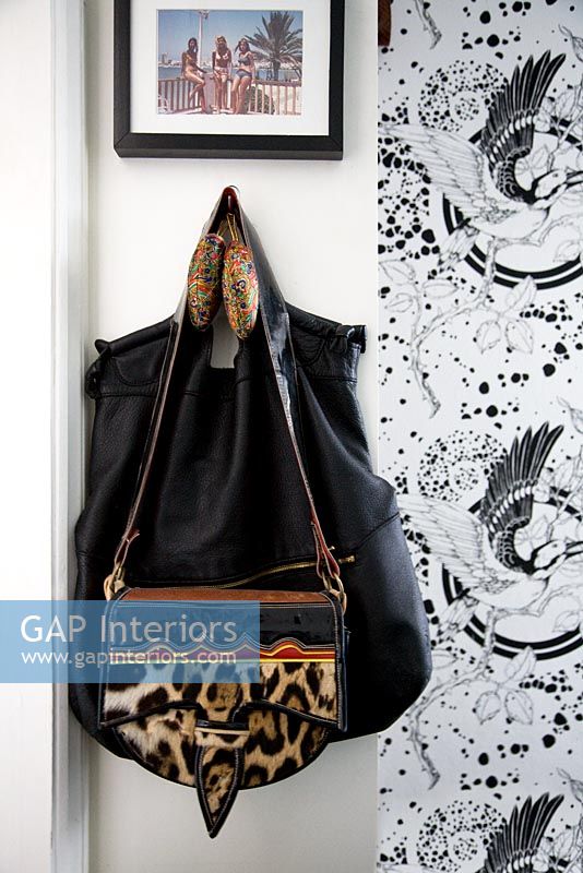 Handbags on hook by patterned wallpaper 