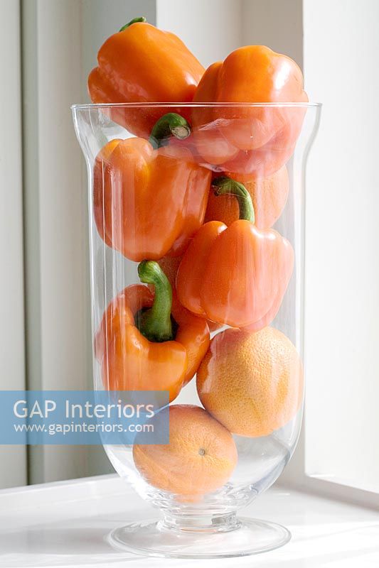 Orange fruit and vegetables in glass vase