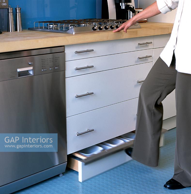 Woman using low level storage in contemporary kitchen