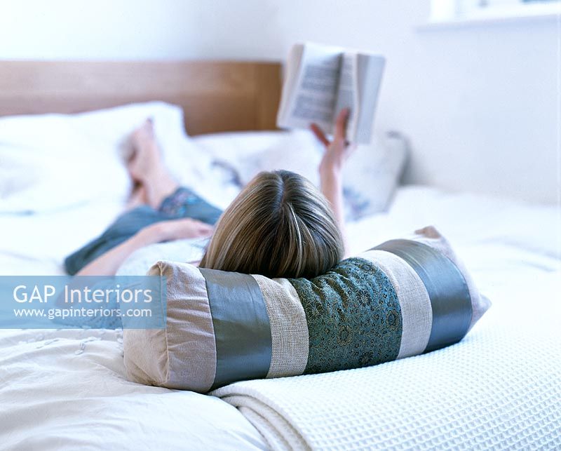 Woman lying on bed reading book 