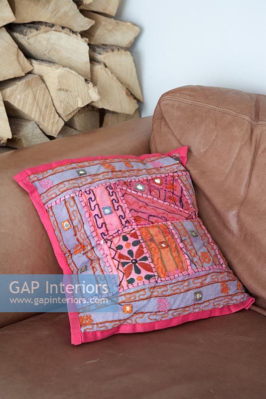Pink patterned cushion on leather sofa 