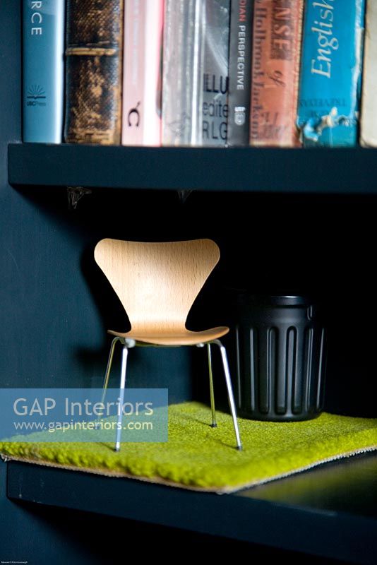 Miniature designer chair on bookshelf 