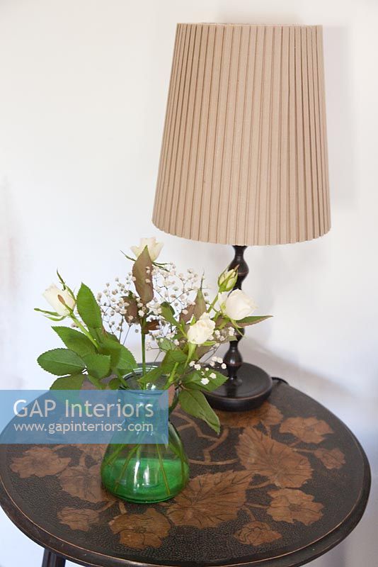 Vase of flowers and lamp on vintage side table 