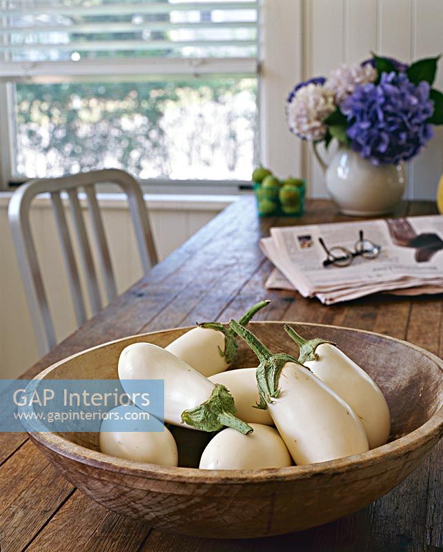 White aubergines in wooden bowl on dining table