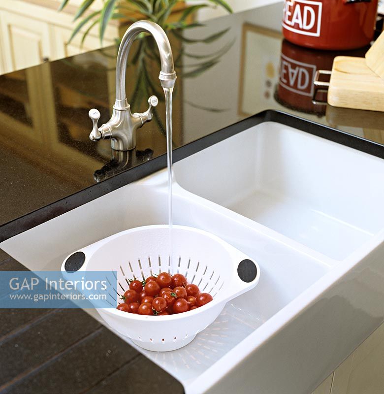 Washing tomatoes in modern kitchen sink 