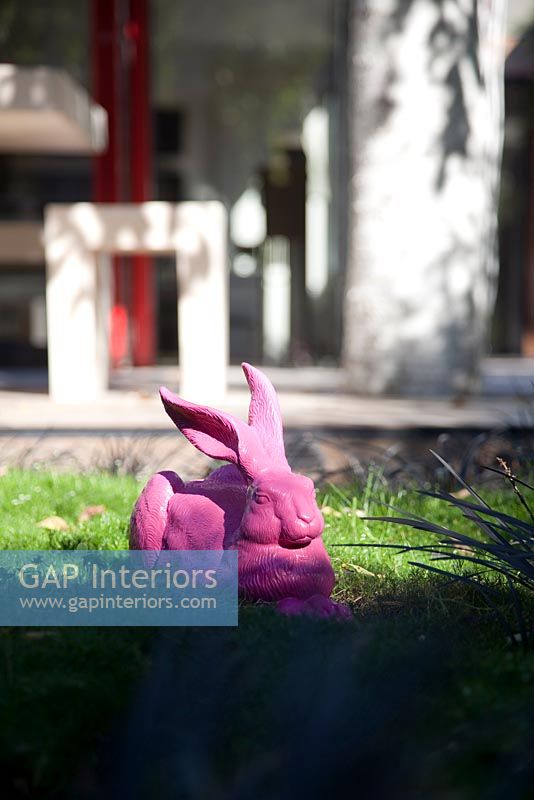 Pink rabbit sculpture in modern garden 