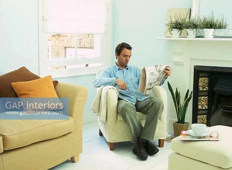 Man sitting reading newspaper in living room 