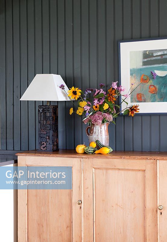Flowers and lamp on wooden sideboard 