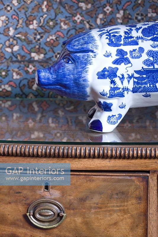 Blue and white piggy bank on an antique chest of drawers