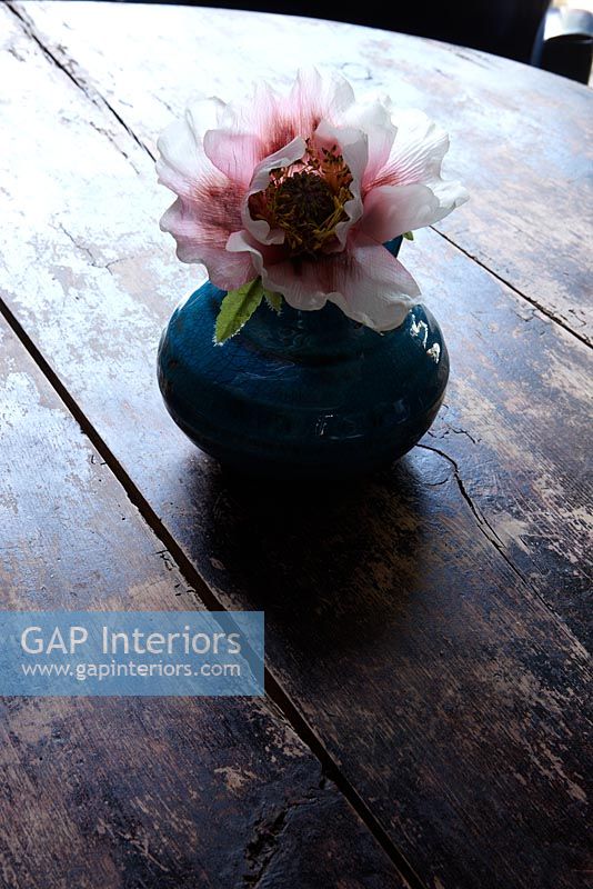 Single flower in vase on wooden side table