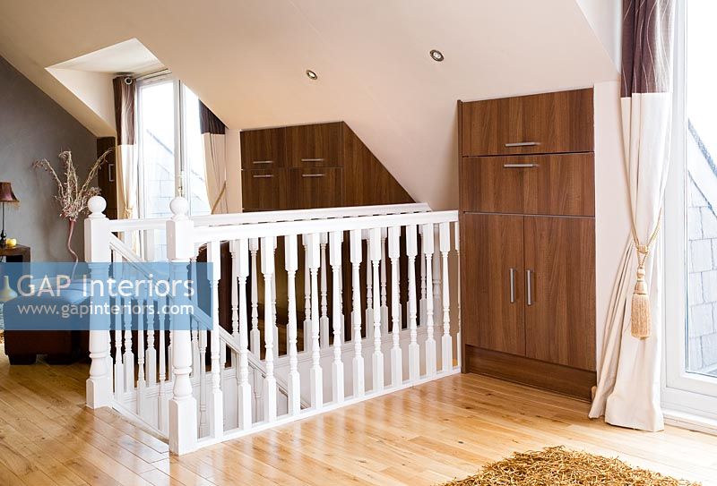 White bannisters and built in cupboards in modern loft room