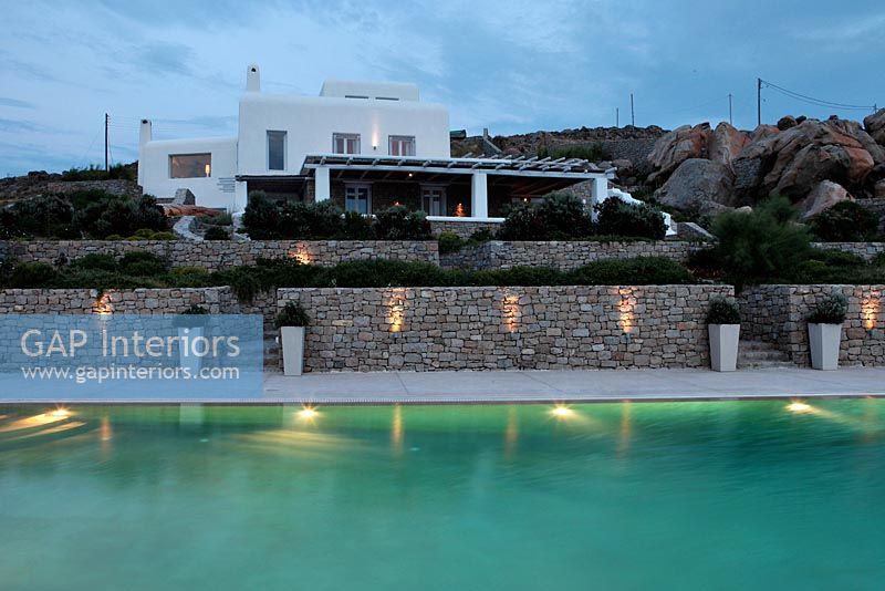 Greek villa with swimming pool lit up at night
