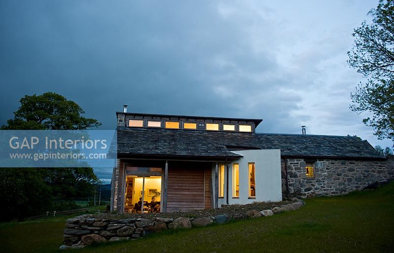 Farmhouse with modern extension lit up at night