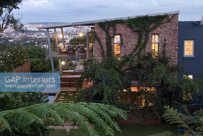 Contemporary house and tropical garden lit up at dusk