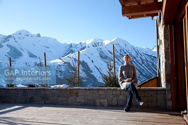 Woman sitting outside chalet with view of Alps