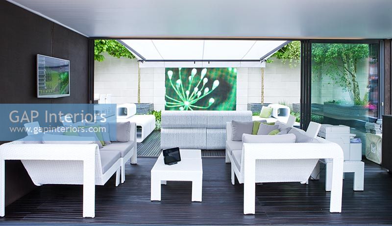 Contemporary lounge area under weather proof canopy with video screen projected on wall - RHS Chelsea Flower Show 2012 